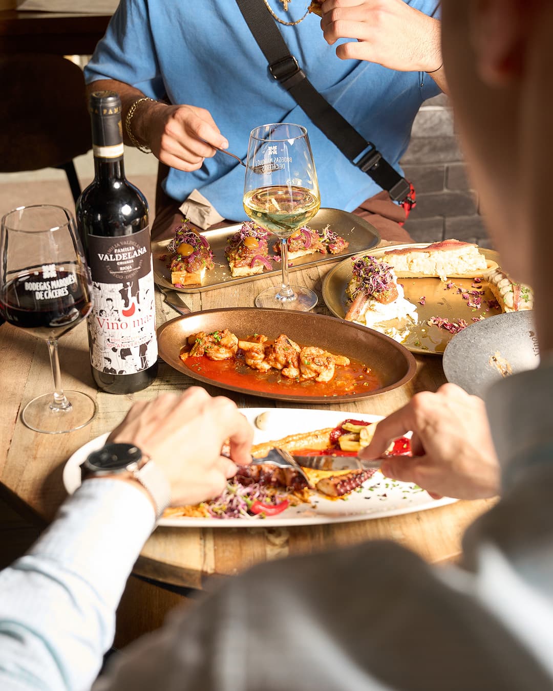 Table with several shared dishes at Vino y Más, Alicante