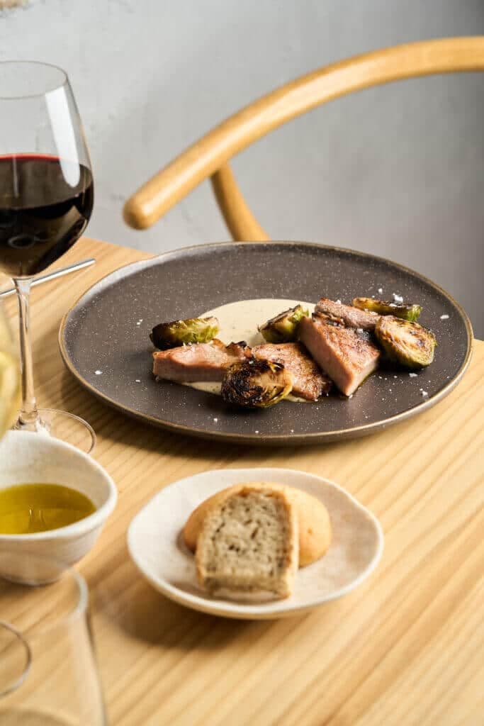 Un plato servido en Alba Restaurante con una copa de vino tinto